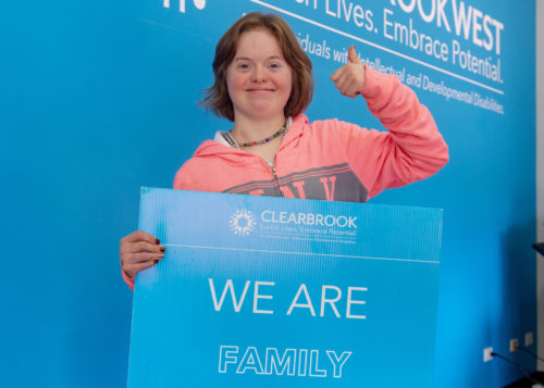 Clearbrook client holds sign that says "we are family"